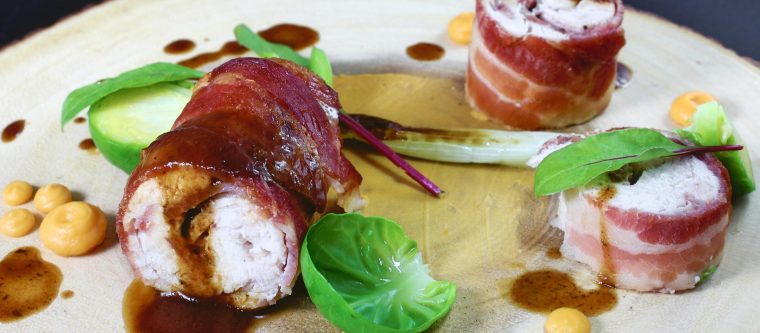 Bacon wrapped stuffed chicken on a wooden cutting board