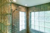 Walk-in shower with green tile and glass block