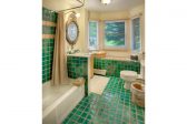 Teal tiled bathroom with bay windows and a shower