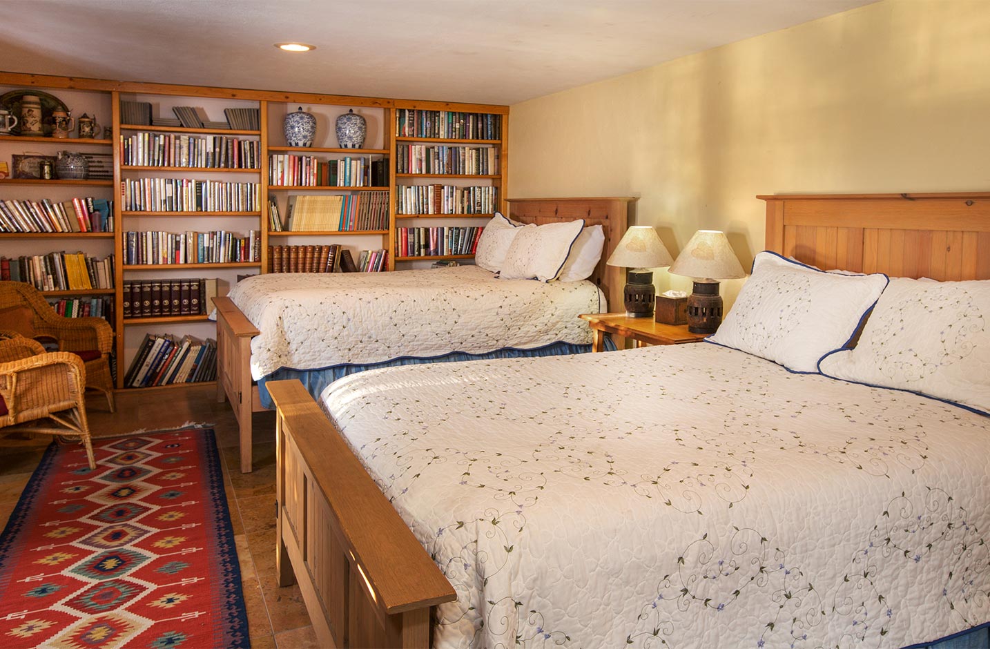 A large room with two queen beds and a bookshelf