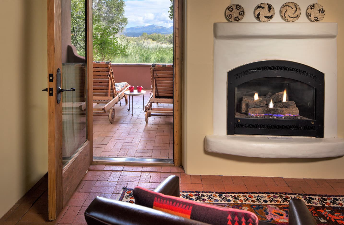 A gas firplace and a patio with two chairs and a view of a mountain