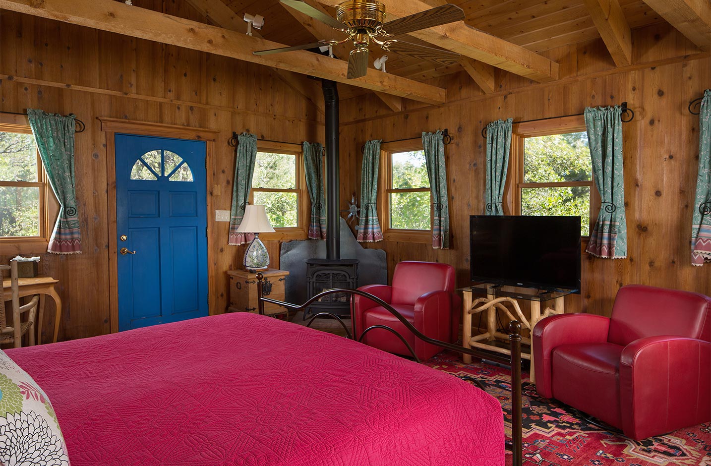 A cabin with a king bed ceiling fam, and flat screen TV