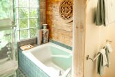 Large tub in a garden room with wooden walls and tile floors