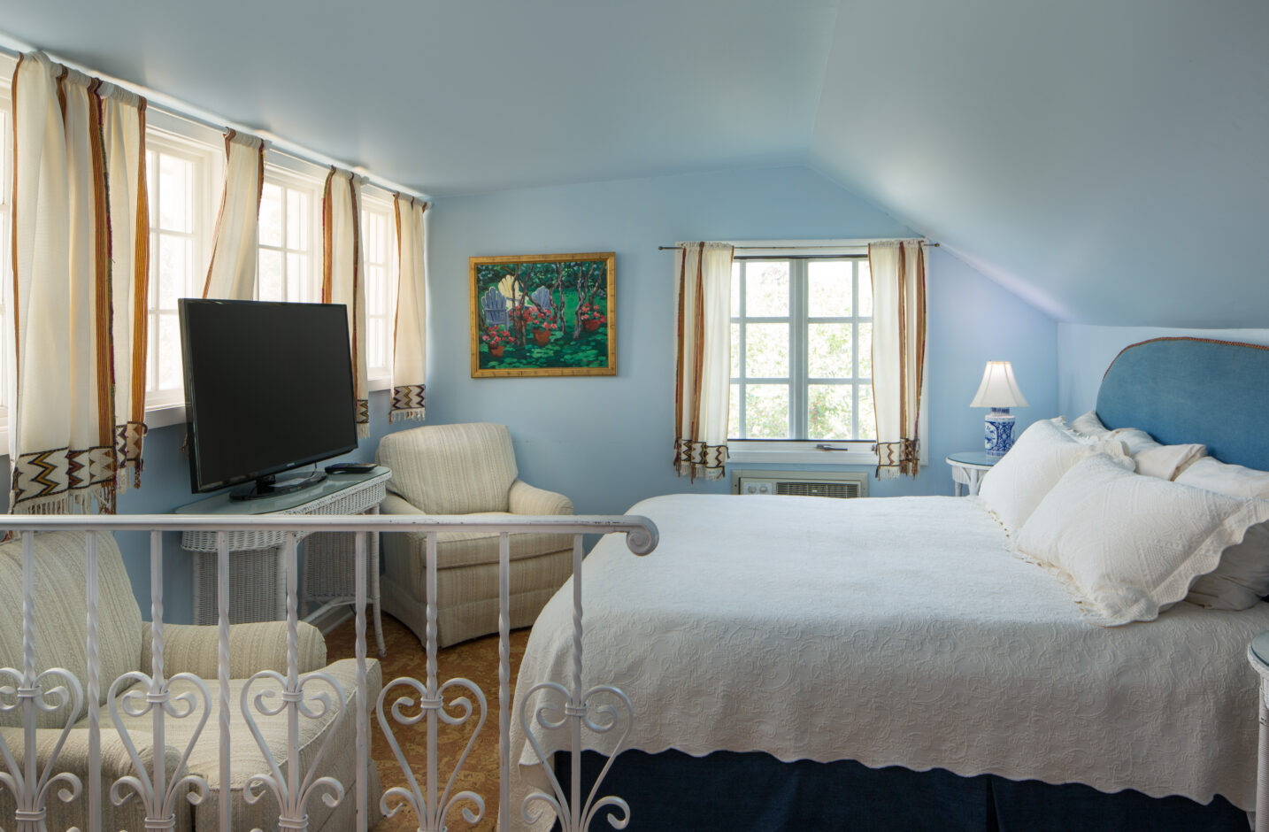 A queen bed and a TV in a room with two windows