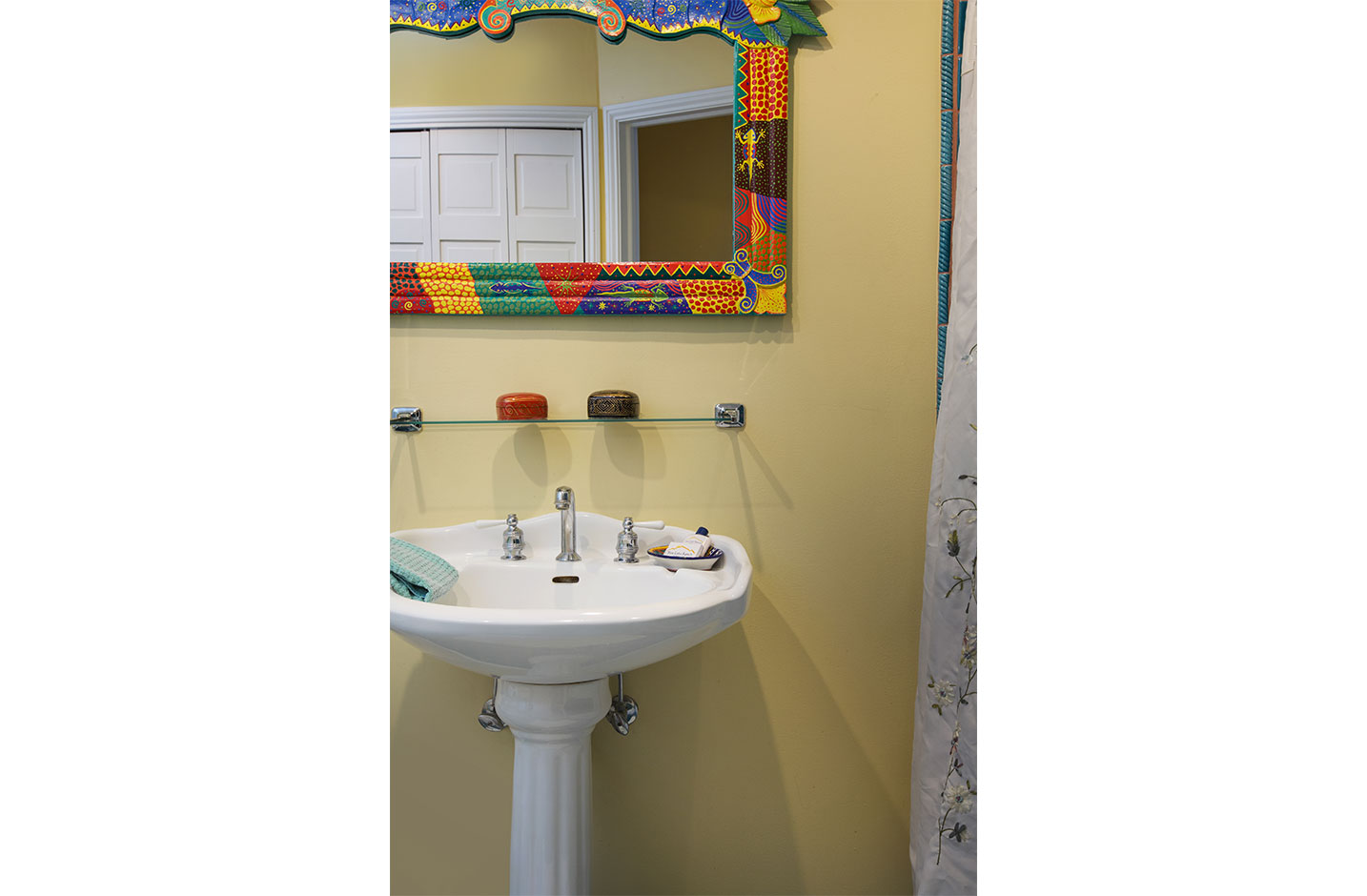 Bathroom sink with a colorful framed mirror