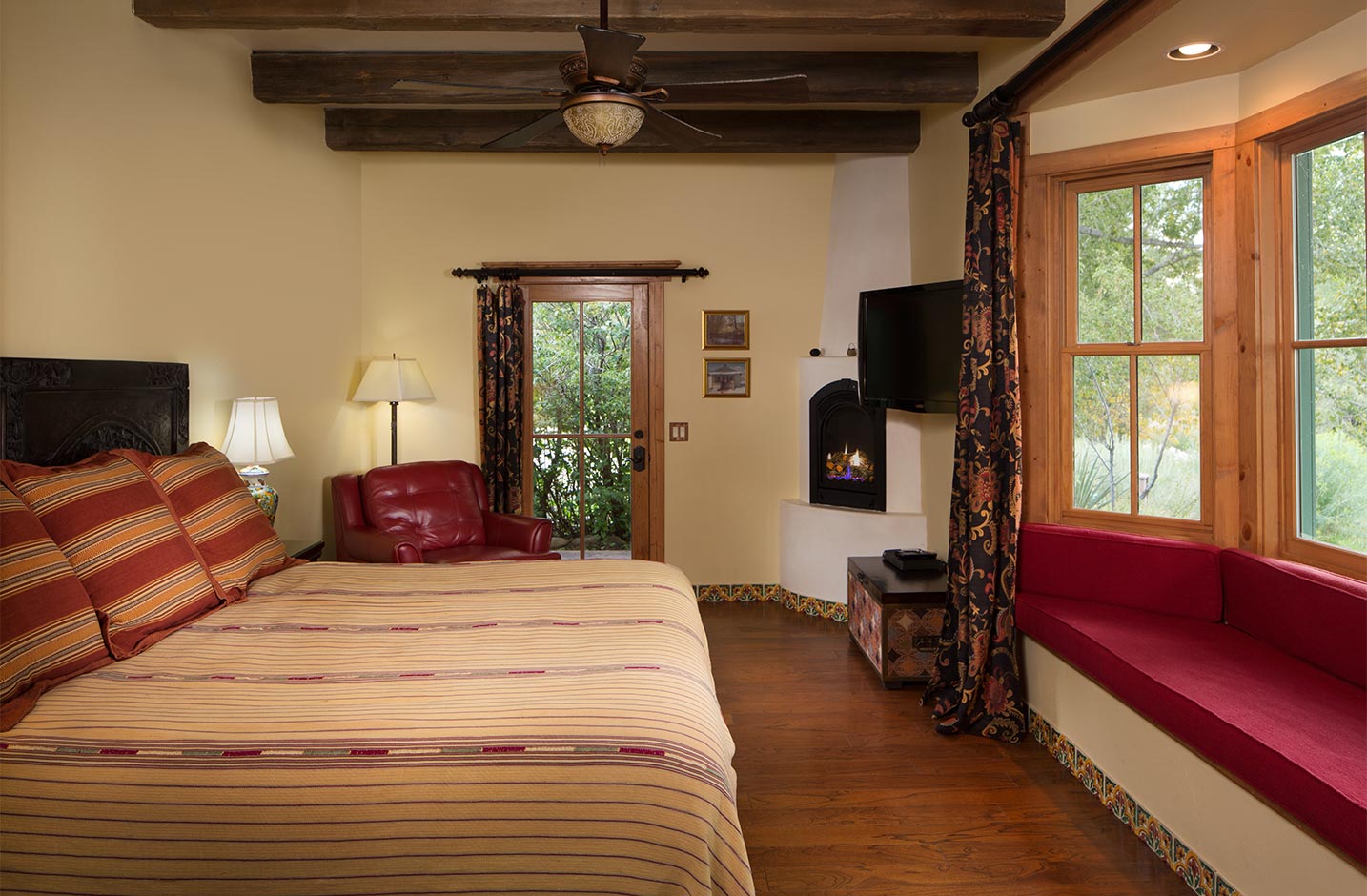 Room with a king size bed, ceiling fan, gas fireplace, a recessed seating area, and door to the outside