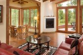 Large living room with leather couch, double doors to the outside patio, and natural light