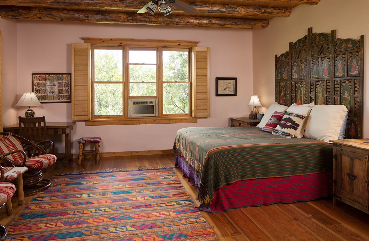 A spacious bedroom with hardwood floors and a king bed and seating area