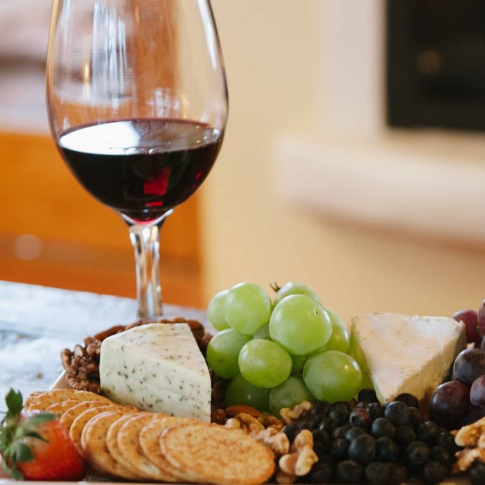 Glass of red wine paired with a plate of assorted cheese and fruit