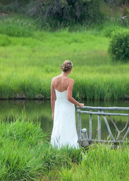 Bride in wedding dress standing near a lake