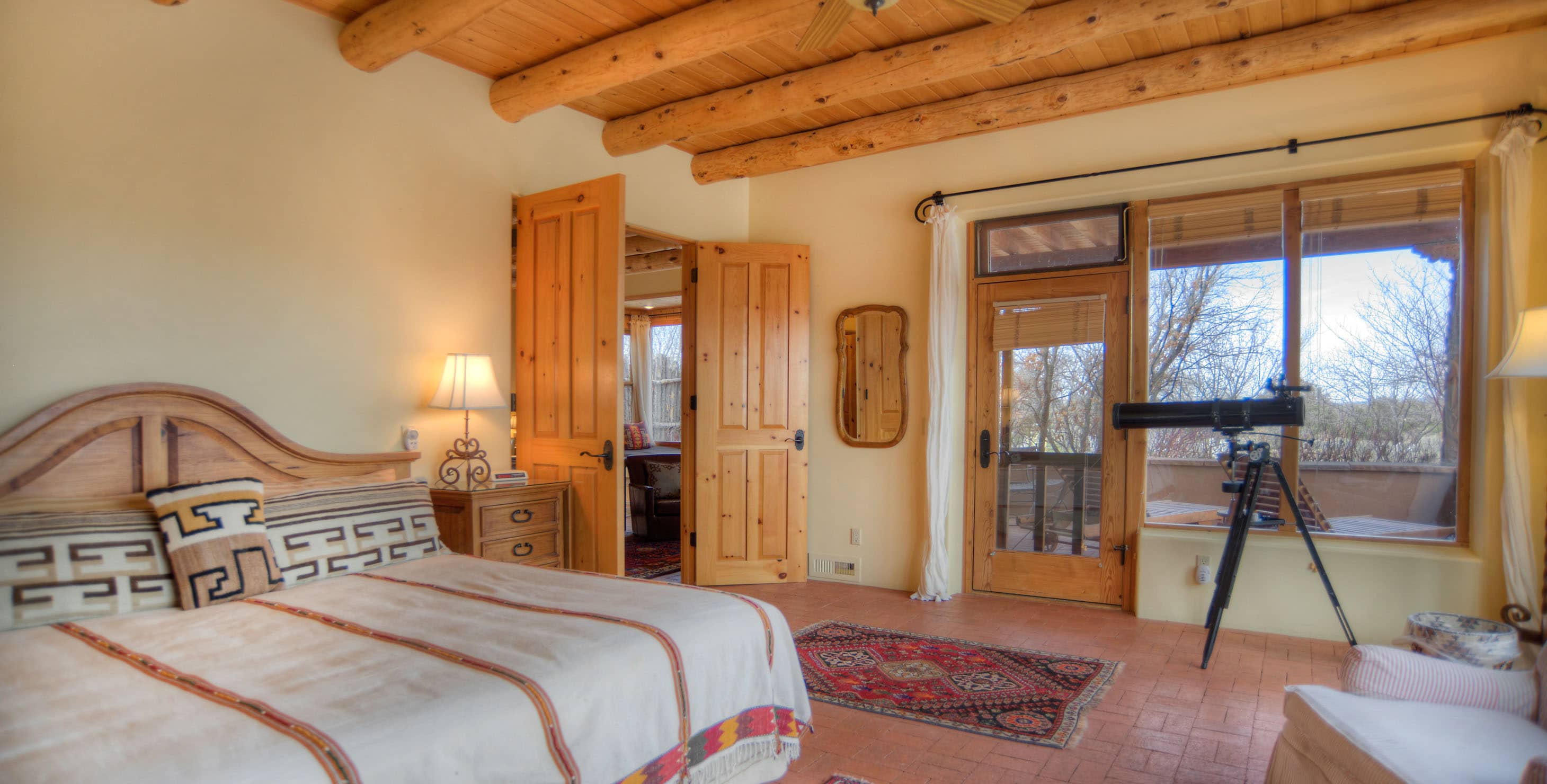 Spacious bedroom with king bed, seating area, double doors, and a doorway to a private patio